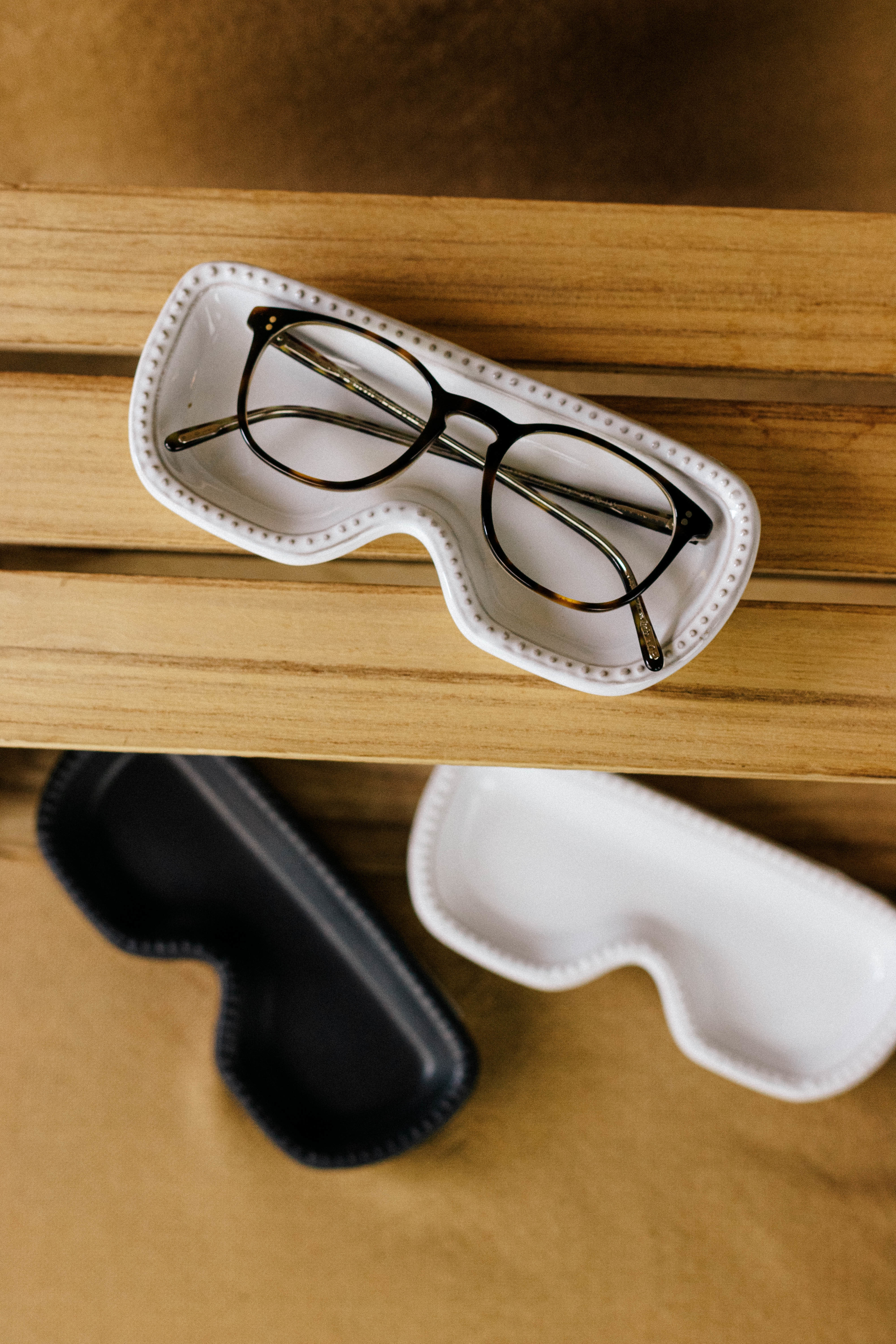 Vertical shot of eyeglasses and black and white cases on a wooden surface